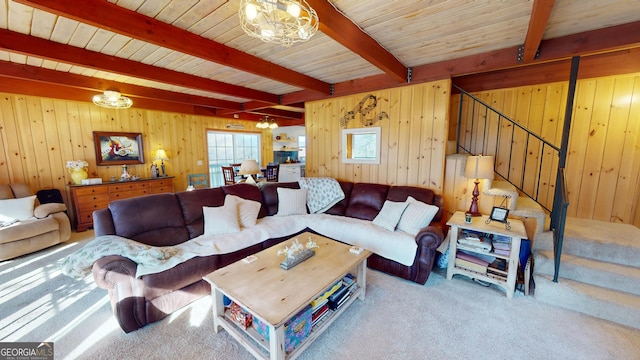 carpeted living area featuring stairs, wooden walls, beam ceiling, and an inviting chandelier