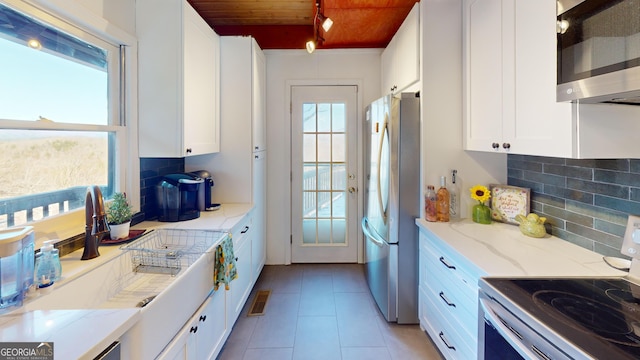 kitchen featuring light tile patterned floors, white cabinetry, appliances with stainless steel finishes, and tasteful backsplash