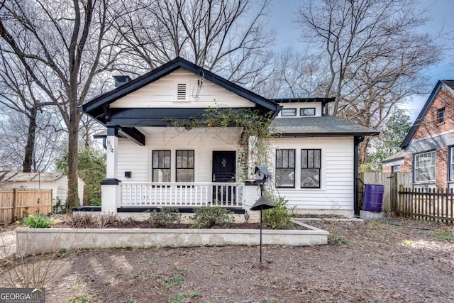 bungalow-style house featuring a porch, roof with shingles, and fence