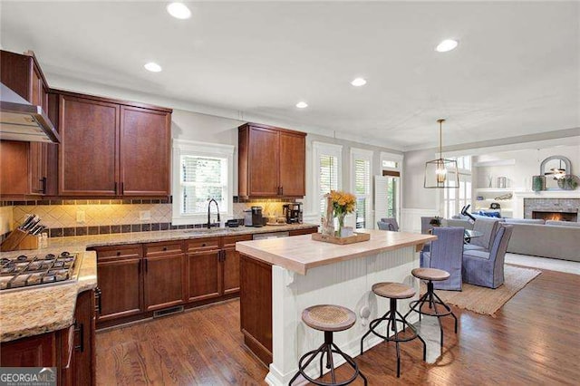 kitchen featuring a kitchen breakfast bar, light countertops, dark wood-type flooring, and stainless steel gas stovetop