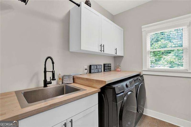 clothes washing area featuring cabinet space, a sink, separate washer and dryer, baseboards, and tile patterned floors