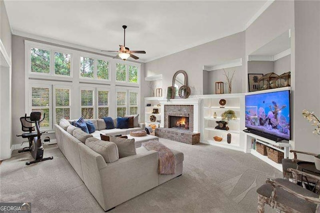 carpeted living room featuring a fireplace, built in features, a ceiling fan, and ornamental molding