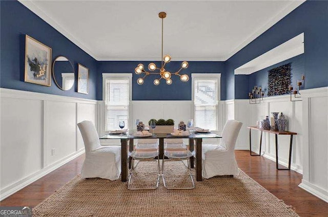 dining space with a decorative wall, wainscoting, wood finished floors, and a notable chandelier