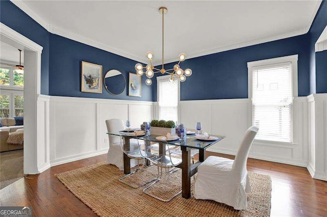 dining space featuring a decorative wall, wainscoting, wood finished floors, and a notable chandelier