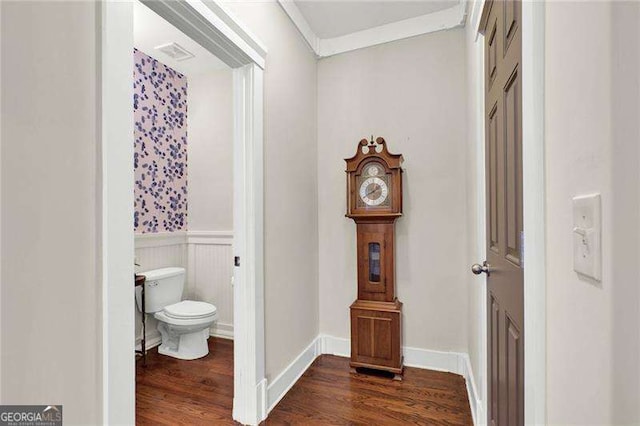 bathroom with toilet, wood finished floors, baseboards, wainscoting, and crown molding