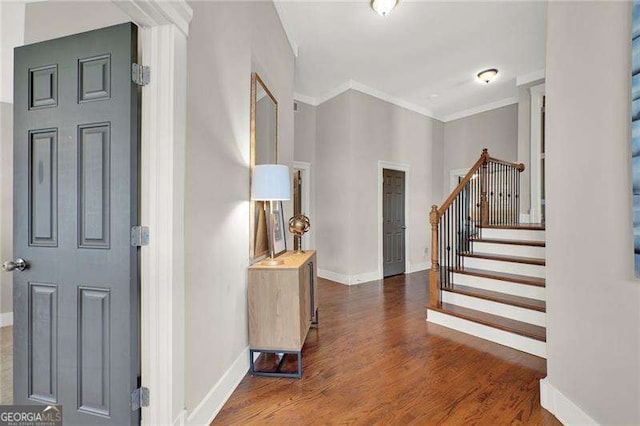 foyer entrance featuring ornamental molding, wood finished floors, baseboards, and stairs