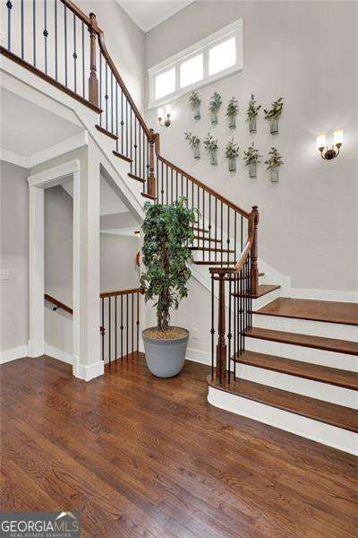 stairs with a high ceiling, wood finished floors, and baseboards