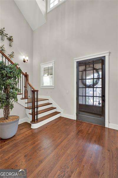 entrance foyer with baseboards, stairs, a high ceiling, and wood finished floors