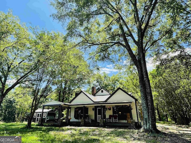 view of front of home featuring a front lawn, covered porch, and a chimney