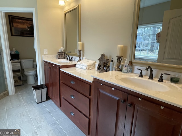 full bathroom with double vanity, tile patterned flooring, toilet, and a sink