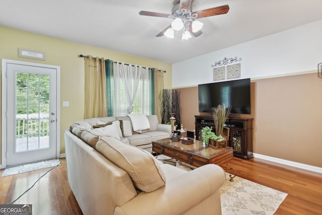 living area featuring wood finished floors, a ceiling fan, and baseboards