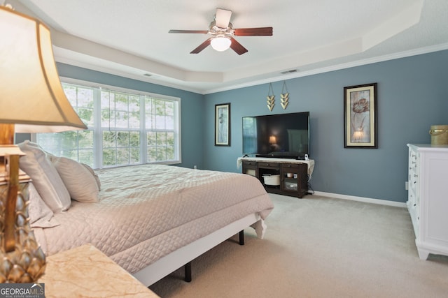 bedroom featuring light carpet, a ceiling fan, visible vents, baseboards, and a tray ceiling