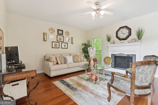 living room featuring baseboards, a premium fireplace, a ceiling fan, and wood finished floors