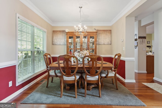 dining area featuring baseboards, crown molding, a chandelier, and wood finished floors