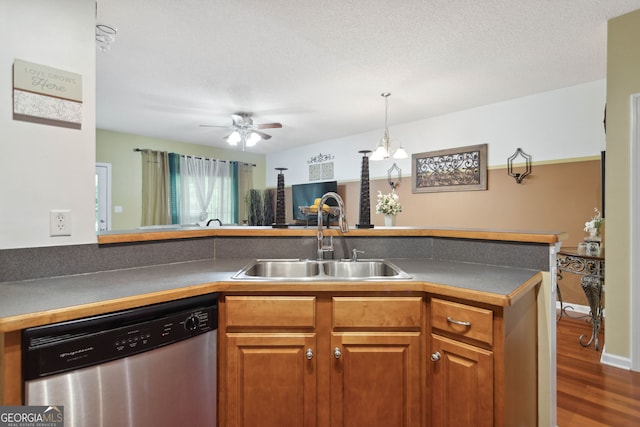 kitchen with brown cabinets, dark countertops, a sink, wood finished floors, and dishwasher