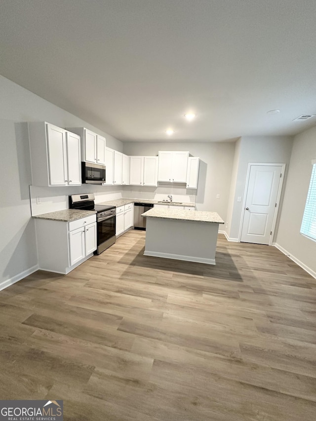 kitchen featuring appliances with stainless steel finishes, a center island, white cabinetry, and light wood-style floors