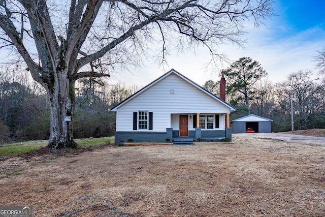 view of front of property featuring an outbuilding, brick siding, and a chimney