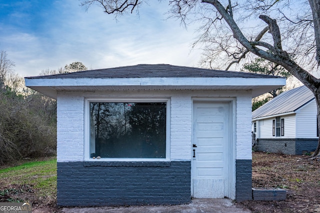 exterior space with brick siding and an outdoor structure