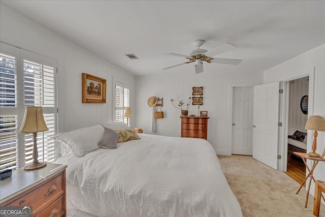 bedroom featuring a ceiling fan, visible vents, and light colored carpet