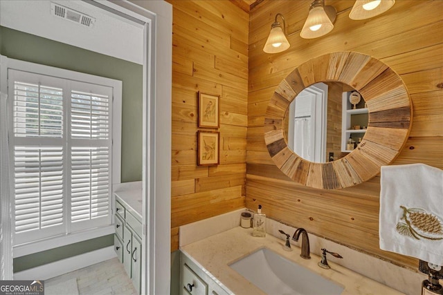 bathroom featuring wooden walls, visible vents, and vanity