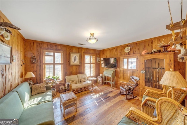 living room featuring wood walls, hardwood / wood-style flooring, and visible vents