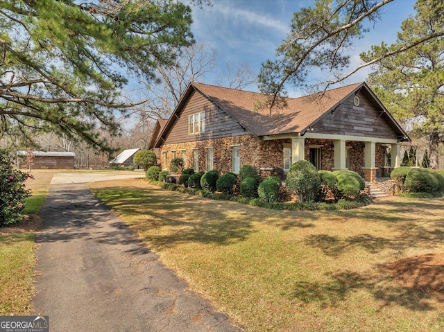 view of home's exterior with stone siding and a yard