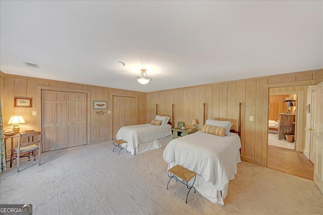 bedroom featuring light carpet, visible vents, and multiple closets