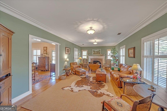 living area with light wood-type flooring, plenty of natural light, visible vents, and a brick fireplace