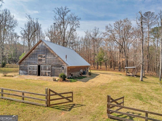 view of side of property featuring an outbuilding, a yard, metal roof, fence, and a barn