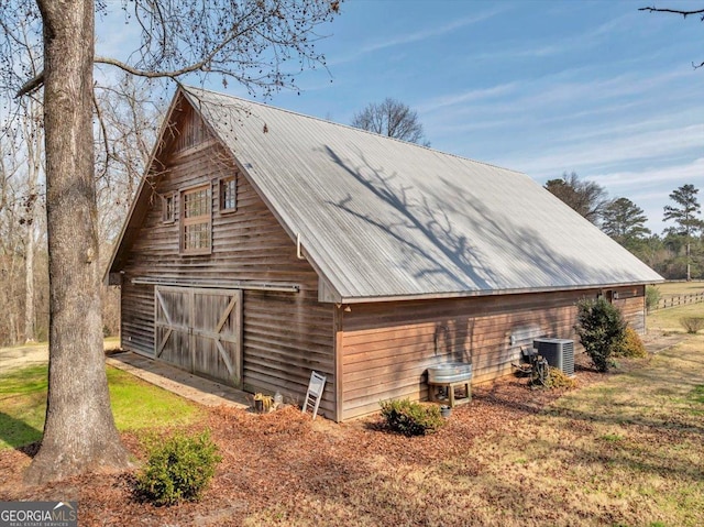 view of property exterior with metal roof, a garage, central AC, an outdoor structure, and a barn