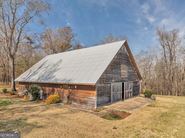 view of property exterior with an outbuilding, a yard, metal roof, a barn, and a garage