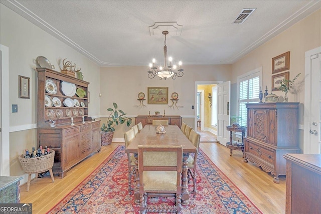 dining room with visible vents, a textured ceiling, light wood-style flooring, and a notable chandelier