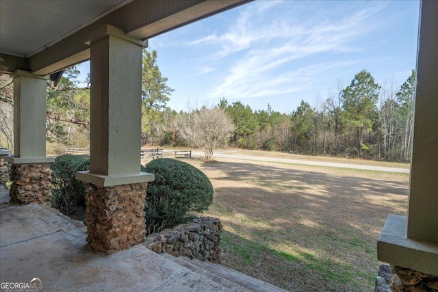 view of yard featuring a porch and a view of trees