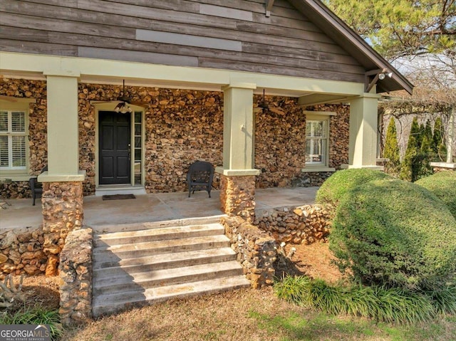 doorway to property with covered porch and stone siding