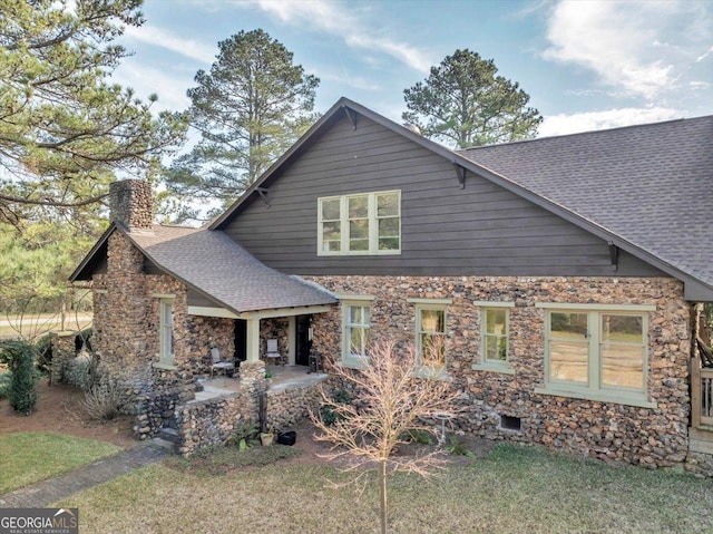 view of front of home with roof with shingles, a chimney, and a patio