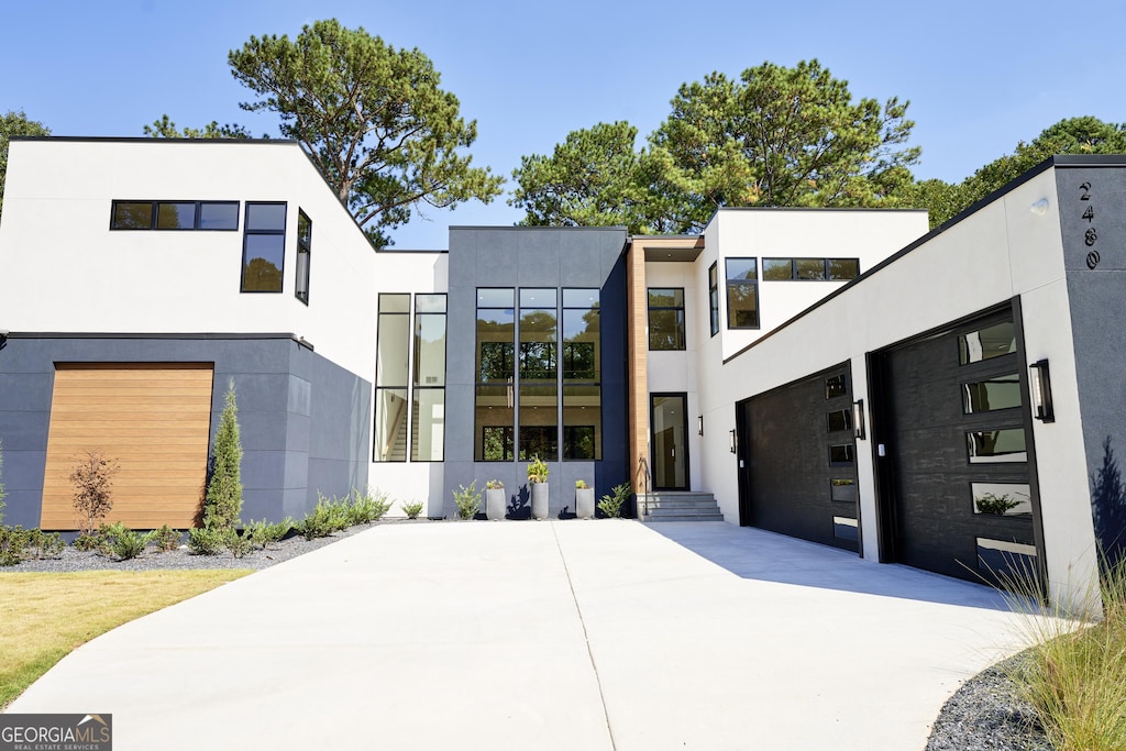 contemporary house with an attached garage, driveway, and stucco siding