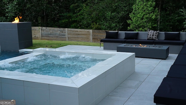 view of swimming pool with an outdoor living space with a fire pit, an outdoor hot tub, fence, and a patio