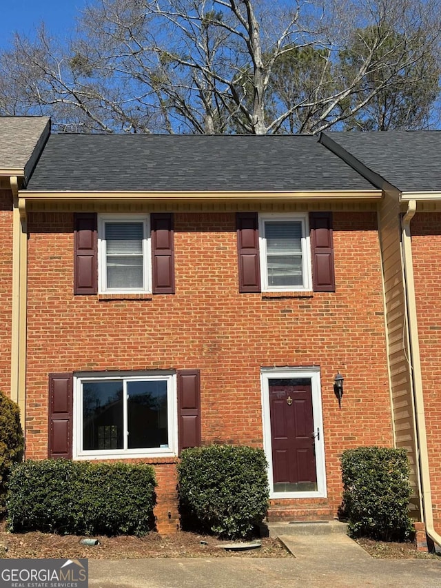 view of property with brick siding and a shingled roof