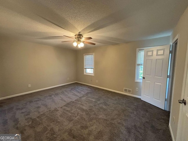 unfurnished room featuring baseboards, dark colored carpet, visible vents, and a ceiling fan