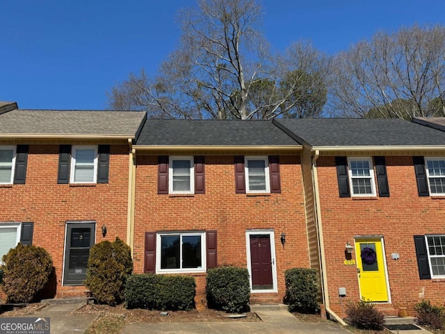 multi unit property with entry steps, brick siding, and roof with shingles