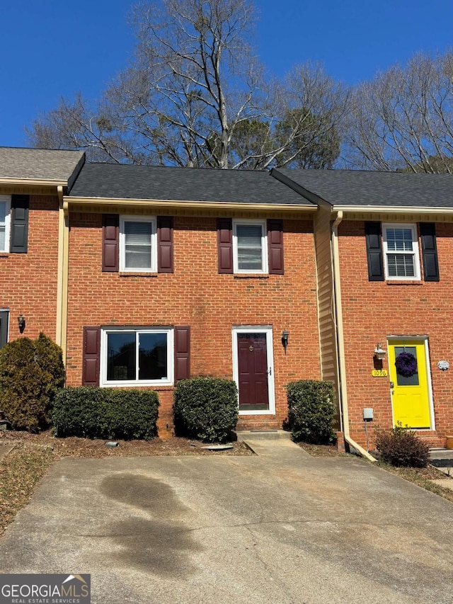 view of property with roof with shingles and brick siding