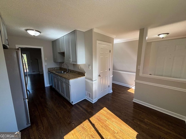 kitchen featuring dark wood-style floors, gray cabinetry, a sink, and freestanding refrigerator