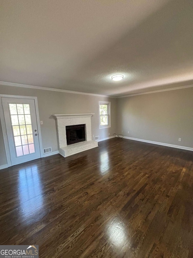 unfurnished living room featuring baseboards, visible vents, ornamental molding, dark wood-type flooring, and a fireplace