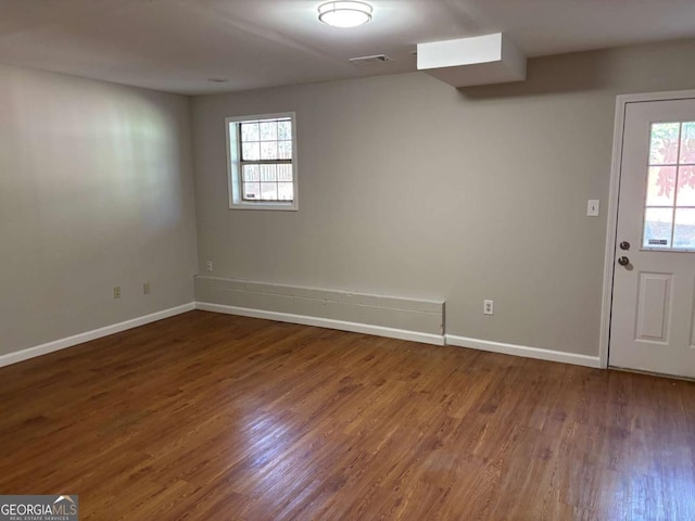 unfurnished room with baseboards, visible vents, a wealth of natural light, and wood finished floors