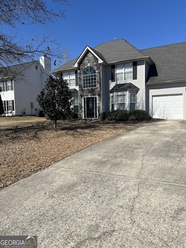 traditional-style home with stone siding, an attached garage, and concrete driveway