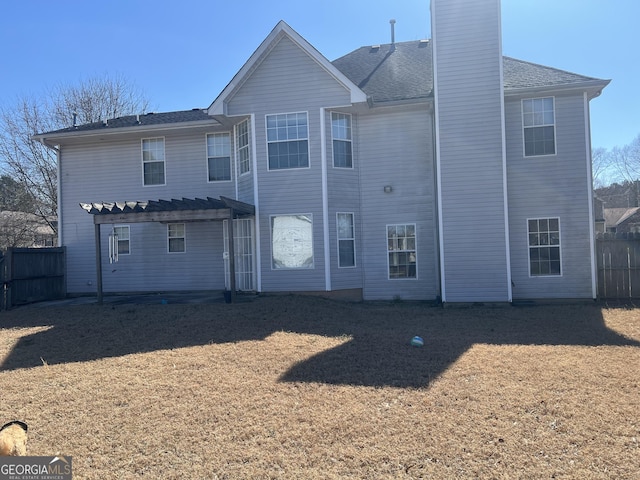 rear view of property with a yard, a chimney, fence, and a pergola