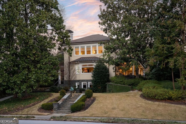 view of front of house with stairs, a standing seam roof, a front yard, and stucco siding