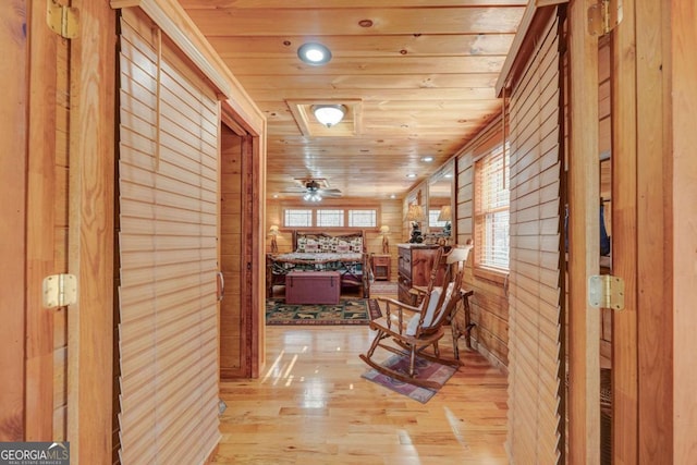 corridor featuring wooden ceiling, wood walls, and light wood finished floors