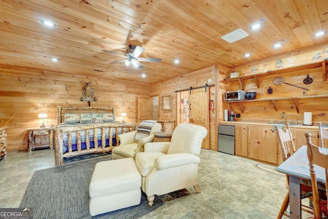 bedroom with a barn door, wood walls, a sink, wood ceiling, and freestanding refrigerator