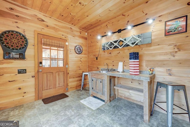 interior space featuring tile patterned floors, wooden ceiling, a sink, and wooden walls